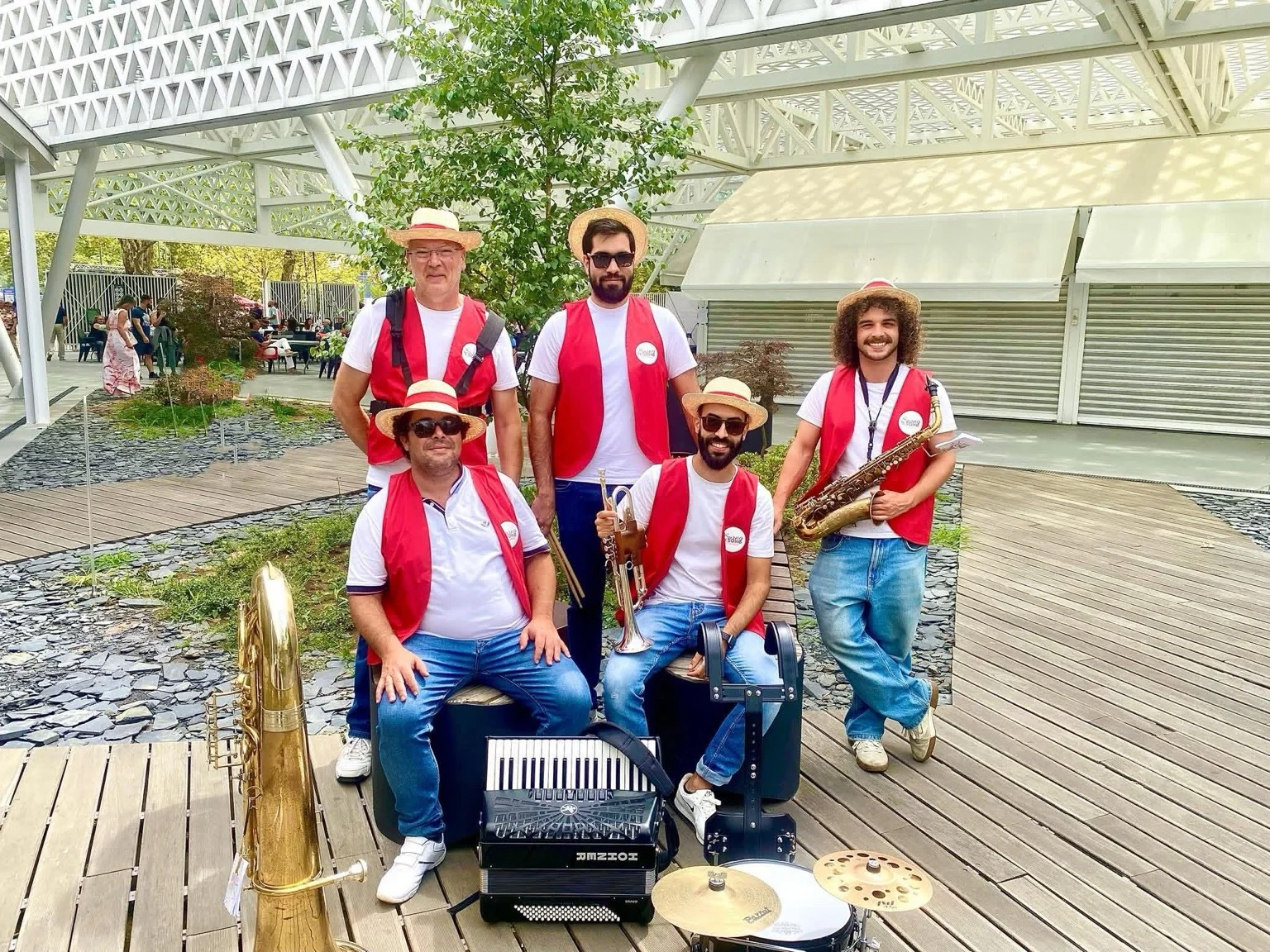 Os cinco músicos dos Swing a Song, de coletes vermelhos, com tuba, acordeão, percussão, trompete e saxofone